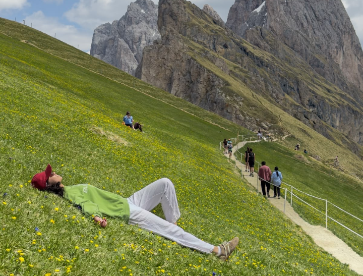 Person taking a peaceful break in a green meadow beside a walking path